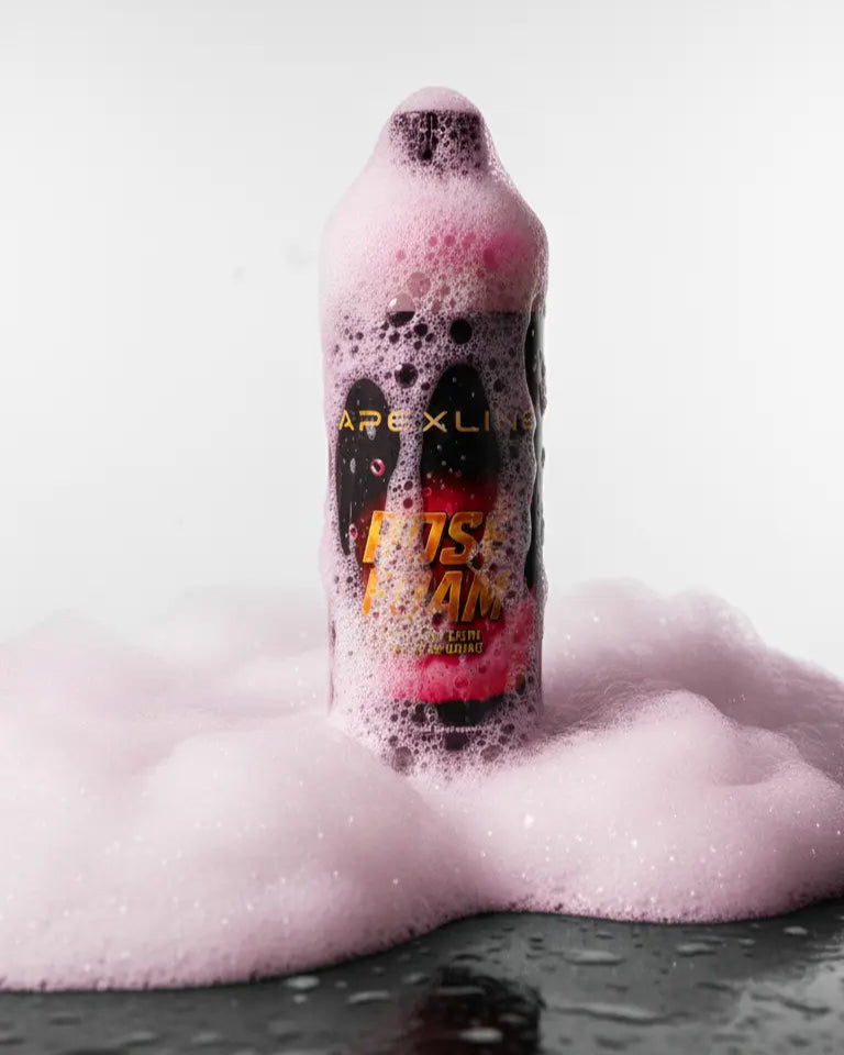 Foto con fondo blanco y champú para coche con agente espumante de color rosa en el centro con espuma alrededor de la botella. Botella de champú rosa para coche PH neutro de alta tecnología.