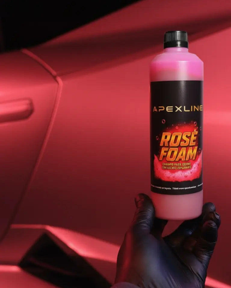 Foto con coche rojo de fondo y champú para coche con agente espumante de color rosa en el centro. Botella de champú rosa para coche PH neutro de alta tecnología.