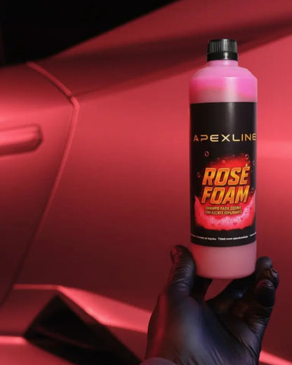Foto con coche rojo de fondo y champú para coche con agente espumante de color rosa en el centro. Botella de champú rosa para coche PH neutro de alta tecnología. 